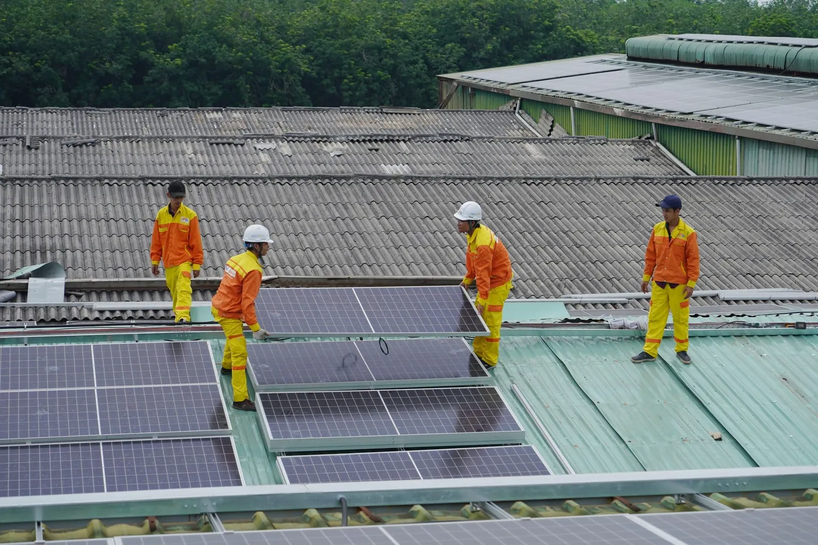 Installation team fitting solar panels across a large flat commercial roof