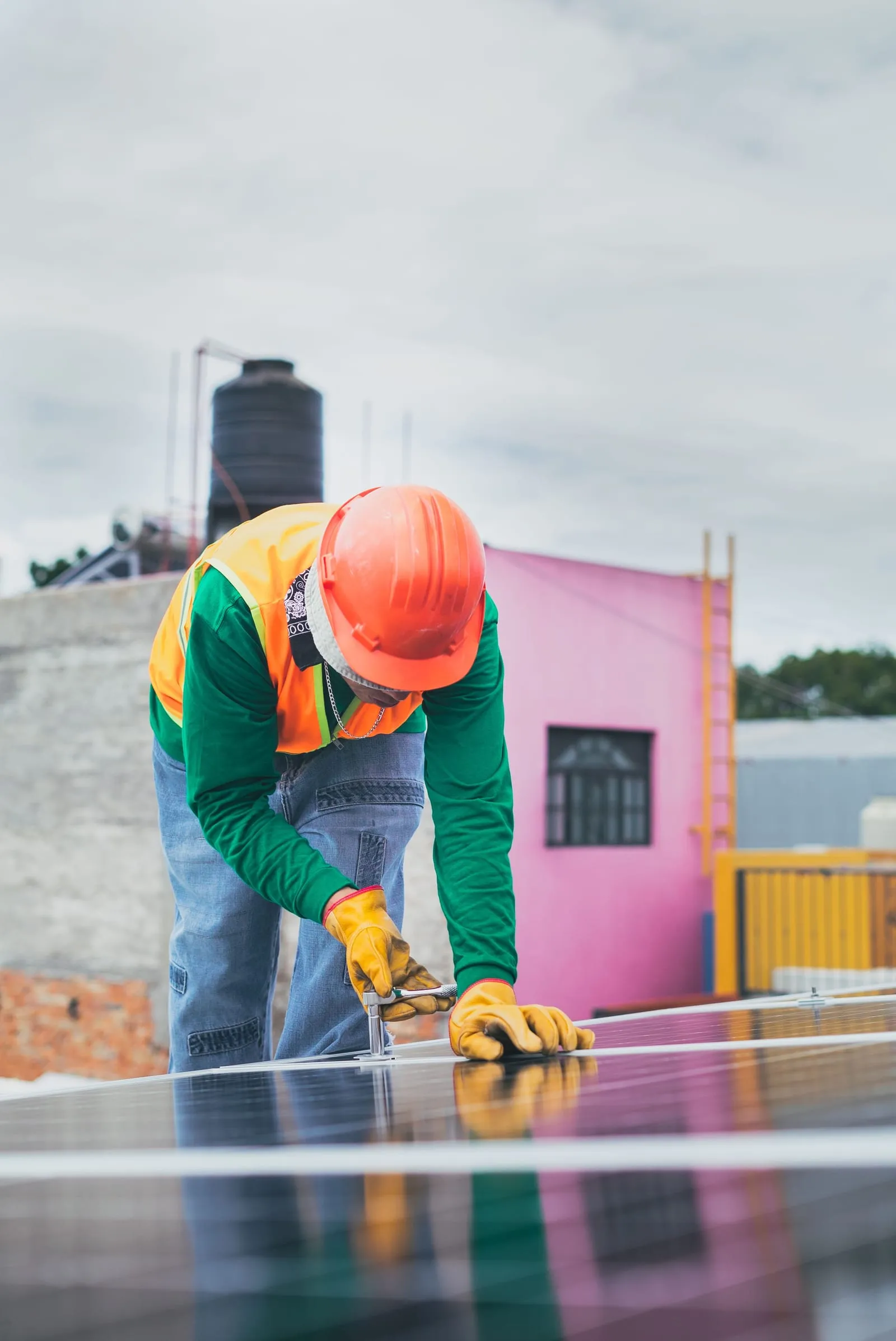 Solar technician in a hard hat working on a residential rooftop